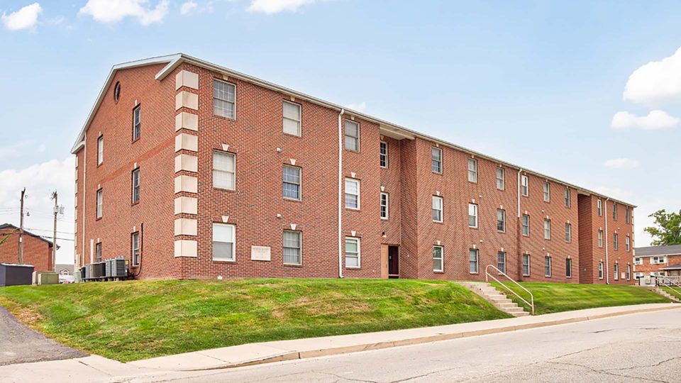 a brick apartment building with a grassy lawn at The Kensington Apartments