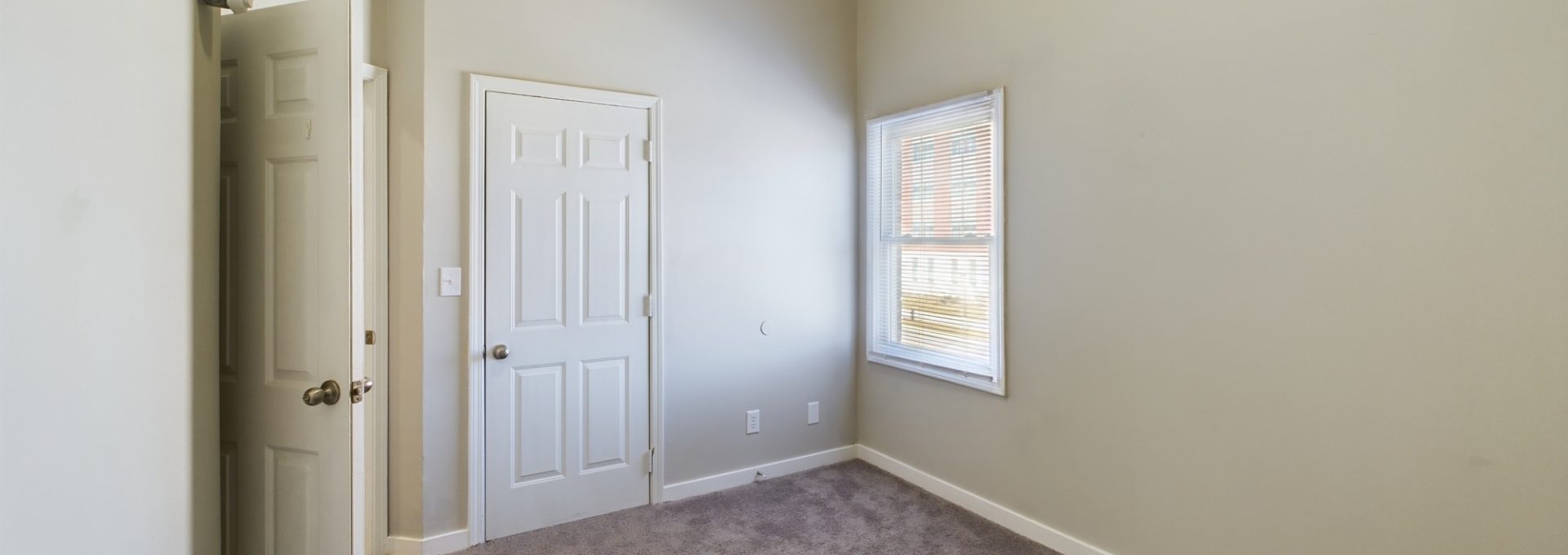 empty room with carpet and door at The Kensington Apartments