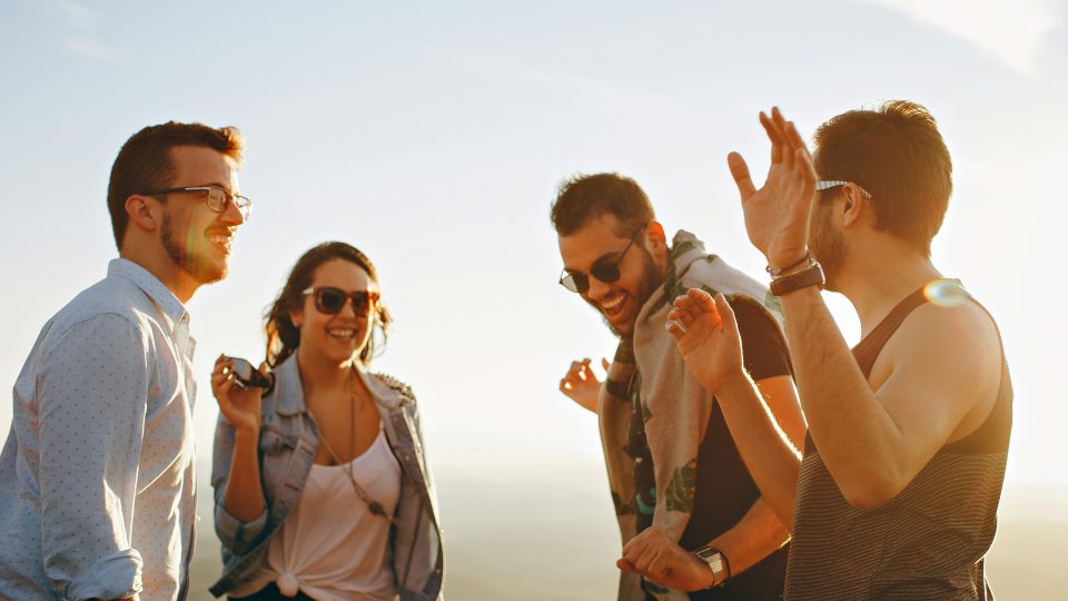 three men and one woman laughing during daytime